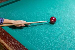 A person holding a cue stick and a ball on a pool table photo