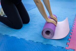 A woman is rolling a yoga mat on the floor photo