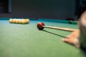 A person's hand is holding a cue stick on a pool table photo