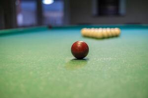 A red ball sits on a pool table photo