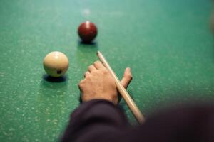 A person holding a cue stick and playing a game of pool photo