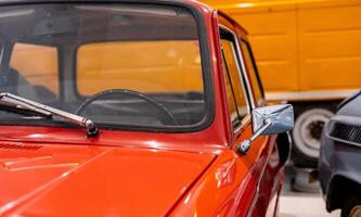 An old red car is parked in a garage photo
