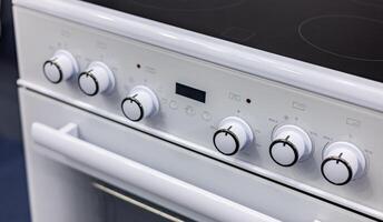 A close up of a white stove with knobs and buttons photo