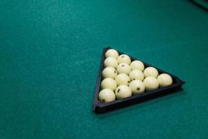 Multi colored billiard balls in the form of a triangle with numbers and cue ball on a pool table. Billiard balls on green table photo