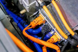 An orange and blue electrical cord is connected to a car photo