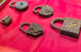 A display of old iron locks on a red cloth photo