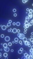 Abstract composition of glowing blue particles resembling floating bubbles on a dark background, evoking a sense of fluidity and motion video