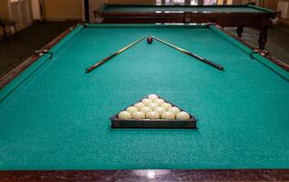 A pool table with two cue sticks and balls photo