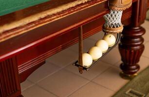 A collection of billiard balls that have entered the hole. There are colorful balls. The ball is under the billiard table. There are defects around the ball due to play photo