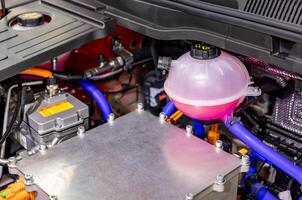 A car engine with a pink water bottle and a hose photo