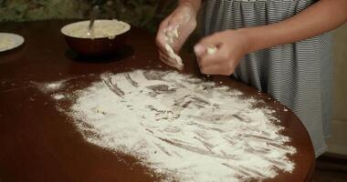 Montage of a baker preparing small balls of dough on a wooden table covered in flour, showcasing the process of portioning and shaping the dough video