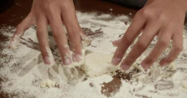 Close up of baker's hands rhythmically kneading and shaping dough on a flour dusted wooden table, demonstrating the process of preparing dough video
