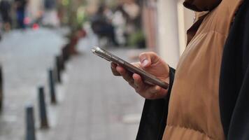 Person checks phone while strolling along a quiet street video