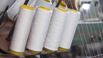 Spools of white thread lined up in a textile workshop video