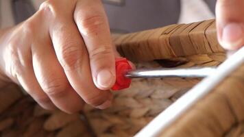 Hand using screwdriver to assemble wicker storage basket at home video