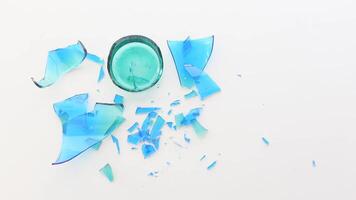 Glass bowl shatters leaving colorful shards on white surface video