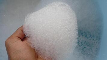 Hand reaching into frothy bubbles in a comfortable bath setting video
