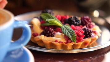 Indulging in berry tart with fresh mint in cozy cafe setting video