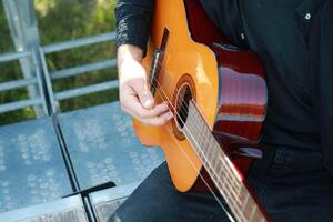 Man Tunes Guitar With Tuning Fork Outside Close up photo