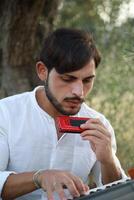Boy Plays Music With Harmonica And Keyboard Among The Olive Trees photo
