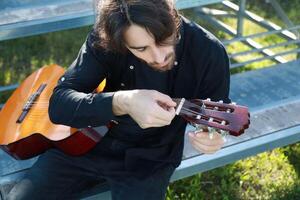 Man's Hand Passes Guitar Strings Preparatively Close up photo