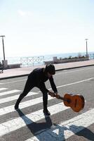 Crazy Young Man Break Up Guitar On Pedestrian Crossings Of A Street In Summer photo