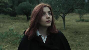 Young Woman With Red Hair Looks Around In A Public Park In Cloudy Cold photo