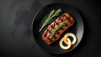 Grilled ribeye beef steak with rosemary and marinated onion, on a black plate photo