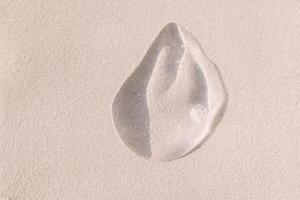 Close-up of a transparent gel smear with bubbles. Cosmetic products. A drop of serum or essence on a textured background. Bright sunlight. photo