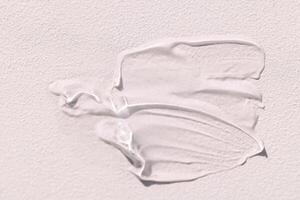 The texture of the cream on a light background. Translucent serum is smeared on the backdrop. The consistency of glycerin gel. Cosmetic smear. photo