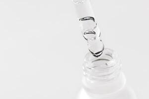 Extreme close-up of a glass pipette with a moisturizing serum with bubbles photo