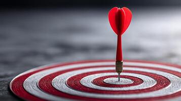 A red dart is perfectly placed at the center of a bullseye target. photo