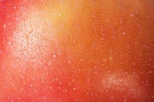 Red with yellow color apple skin macro photo as background. Texture of apple with water drops.