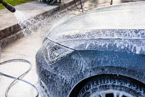 Car wash process showcasing foam being sprayed on a vehicle at an auto detailing location photo