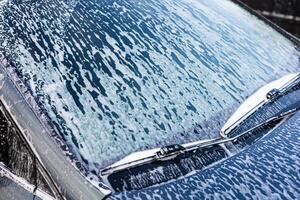 Washing a car with soap on a sunny day in a driveway near the home photo