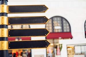 Directional signpost with blank arrows in a bustling shopping area during daytime photo