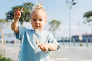 Child enjoys a sunny day outdoors while holding a delicate flower in a scenic park photo