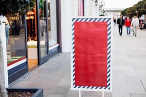 Signboard stands outside a shop on a busy street during the afternoon in a shopping district photo