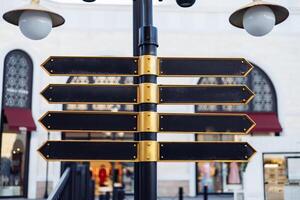 Directional signpost stands in a shopping district with multiple blank arrows for guidance photo