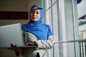 Professional Woman Using Laptop in Modern Work Environment by Window photo