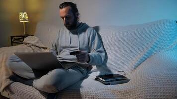 Man Using Laptop and Credit Card While Relaxing at Home in Evening Setting photo