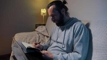 Focused Man Working With Laptop and Notepad in Cozy Home Setting photo