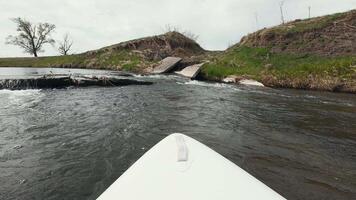 A kayak is paddling down a river with a bridge in the background video