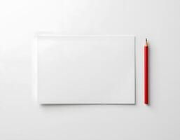 A blank notepad with a red pencil on a white surface, perfect for writing and drawing. photo