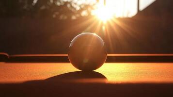 Dynamic silhouette of a pool ball with sunset glow over a billiard table in a serene setting photo
