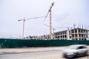 A construction site with cranes and a tall building in the background photo