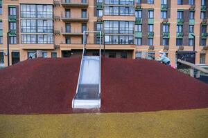 A child is sliding down a slide in front of a building photo