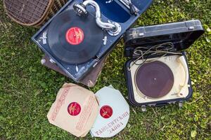 Moscow, Russia, 09.10.2017. A record player sits on a grassy field with a few records on top of it photo