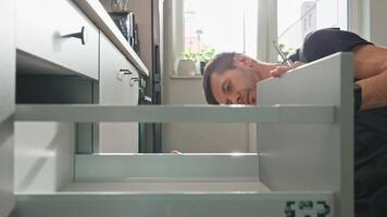 Handyman installing and adjusting drawer slide mechanism in kitchen cabinet. Furniture installation video