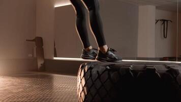 An athlete showcases impressive tire jumps, demonstrating both strength and agility within a modern gym environment, highlighting a steadfast commitment to fitness and functional training routines video